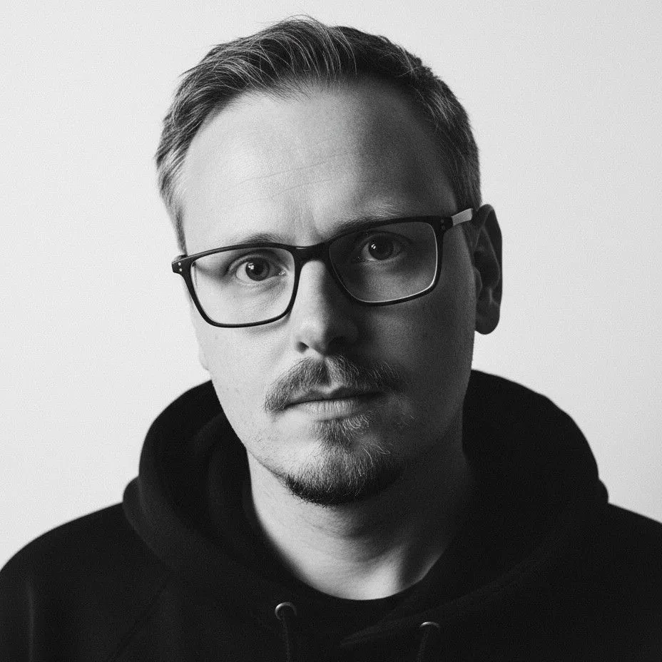 Ruandré, in glasses and a dark hoodie, looking straight at the camera.